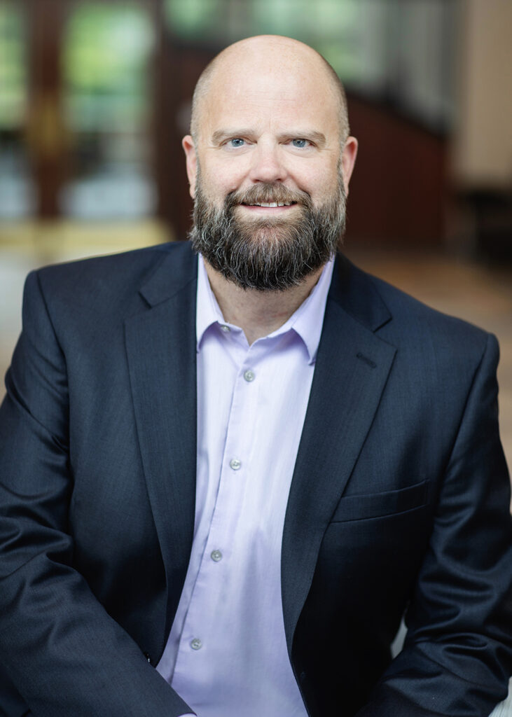 Picture of Accra Chief Financial Officer Chad Derner, wearing a suit jacket and light purple button down shirt