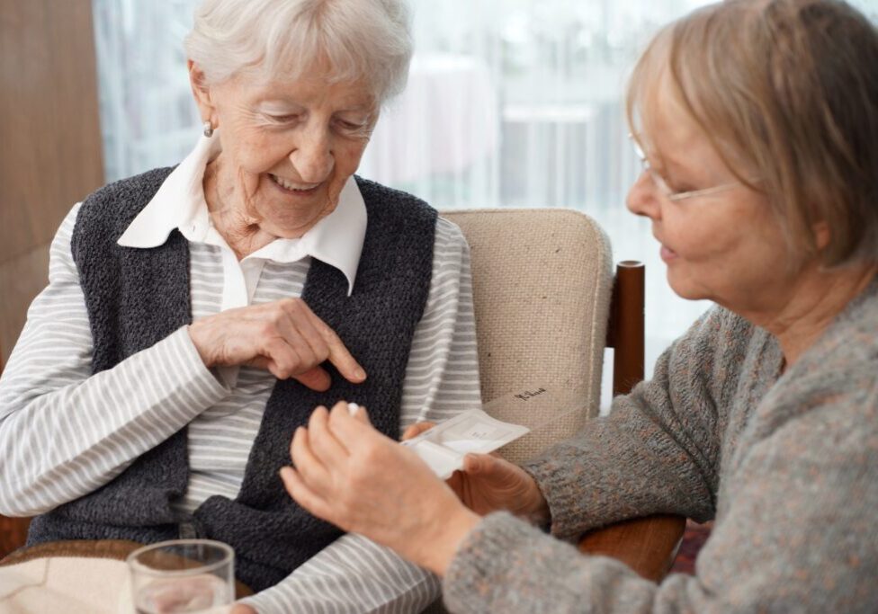 A caregiver helps a senior client take her medications.