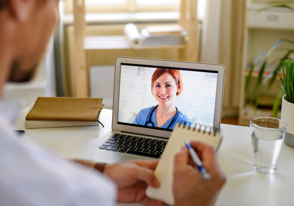 An unrecognizable man having video call with doctor at home, online consultation concept.